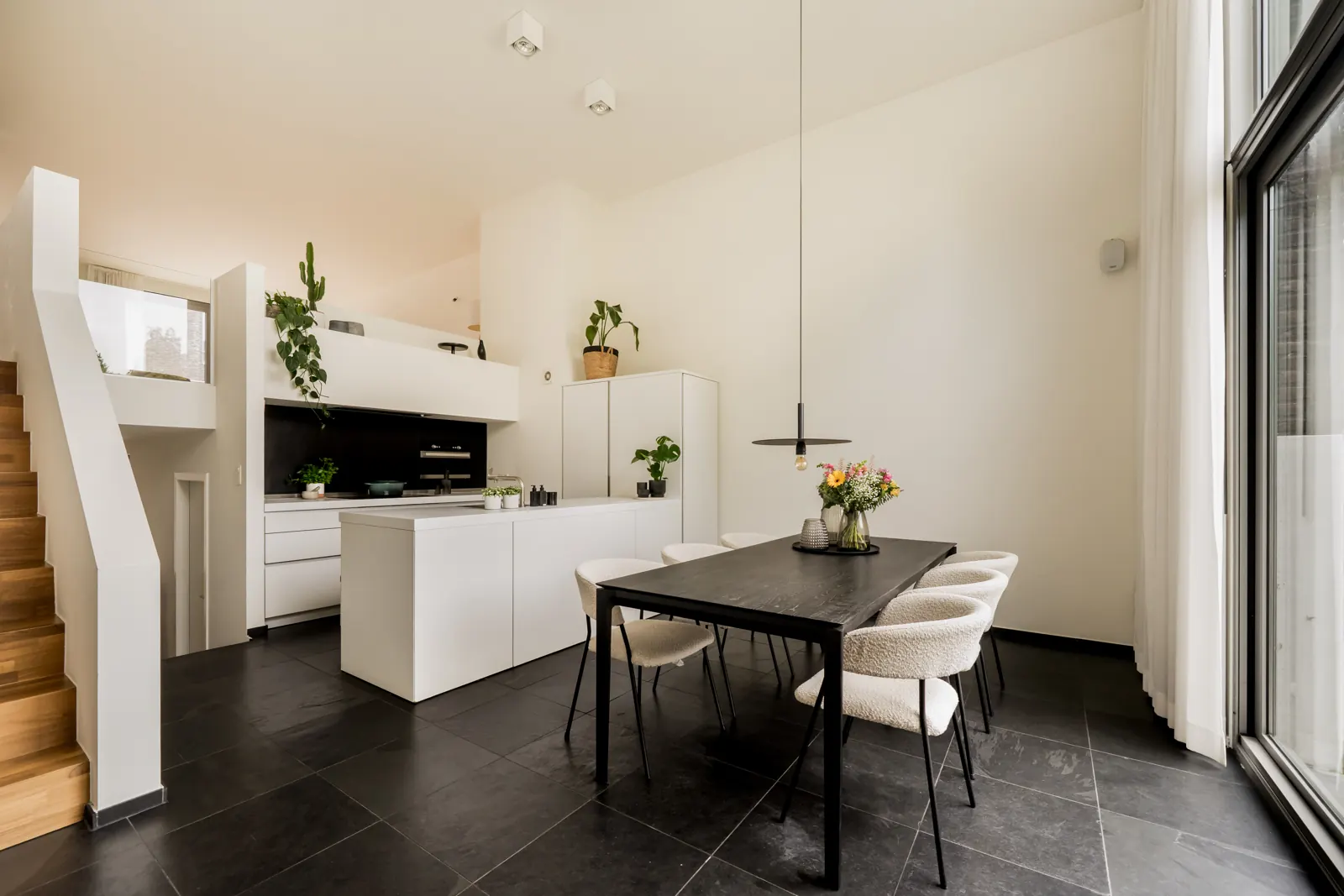 Keuken en eetplaats onder de vide, met open trap naar de mezzanine